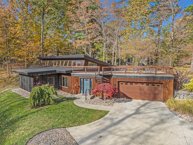 view of front of house with a sunroom, a front lawn, and a garage