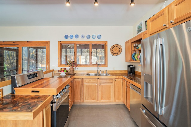 kitchen featuring wooden counters, rail lighting, sink, light tile patterned floors, and stainless steel appliances