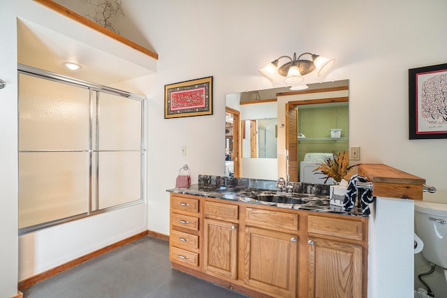 full bathroom with concrete floors, bath / shower combo with glass door, washer / dryer, toilet, and vanity