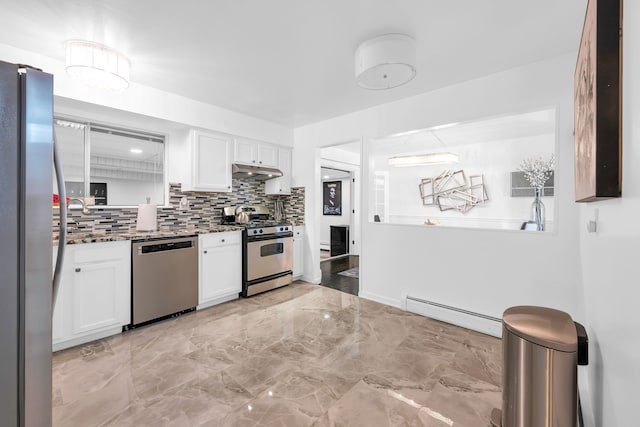 kitchen with decorative backsplash, dark stone countertops, baseboard heating, appliances with stainless steel finishes, and white cabinetry