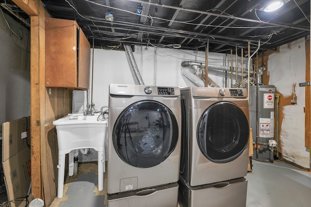 laundry area featuring washing machine and clothes dryer, cabinets, and gas water heater