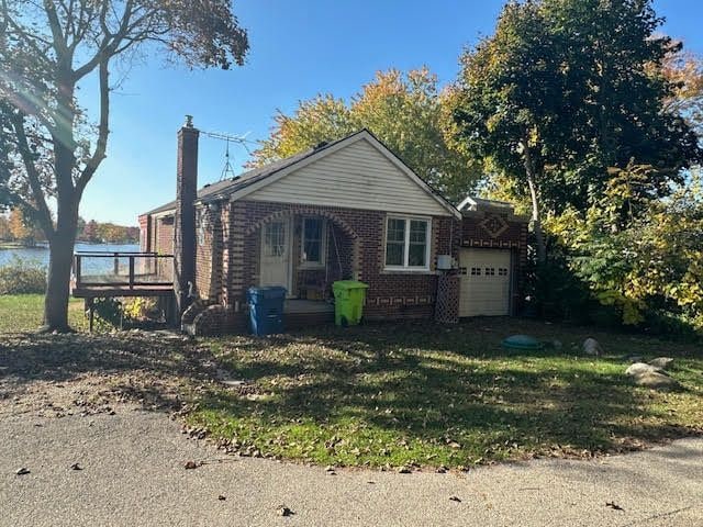 view of front of house featuring a garage, a deck with water view, and a front yard