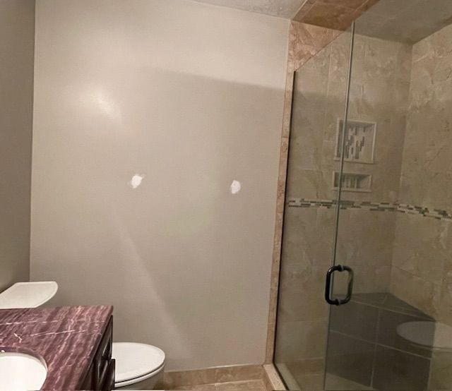 bathroom featuring tile patterned floors, vanity, toilet, and a shower with shower door