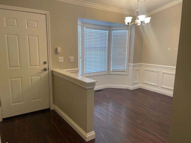 interior space featuring dark hardwood / wood-style flooring, an inviting chandelier, and crown molding