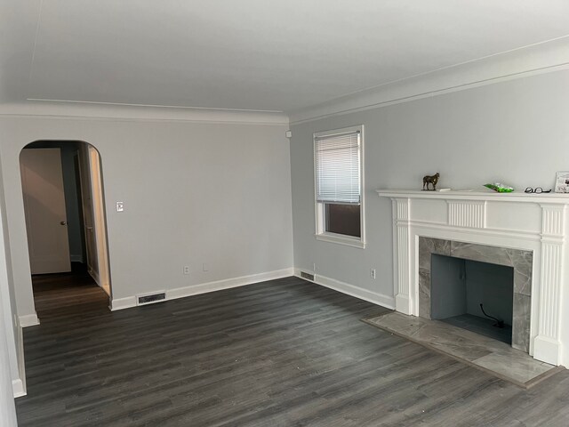 unfurnished living room with a premium fireplace, dark wood-type flooring, and ornamental molding