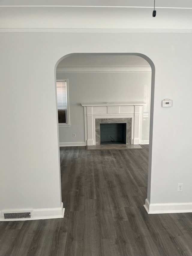 unfurnished living room featuring a fireplace, dark wood-type flooring, and ornamental molding