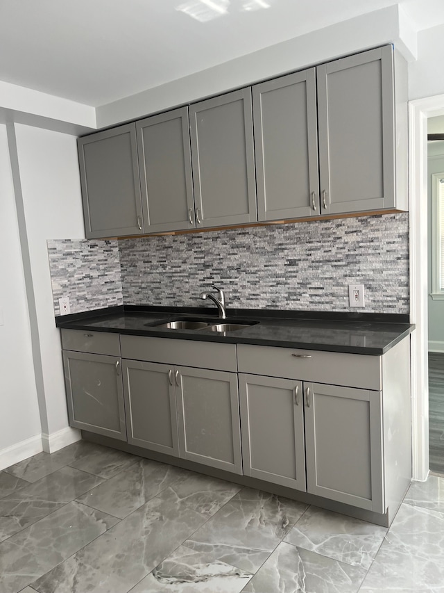 kitchen featuring gray cabinetry, decorative backsplash, and sink