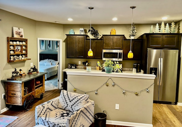 kitchen with light hardwood / wood-style floors, dark brown cabinetry, stainless steel appliances, and hanging light fixtures