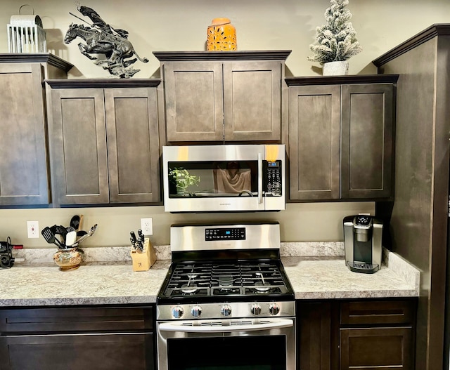 kitchen featuring light stone countertops, dark brown cabinets, and appliances with stainless steel finishes