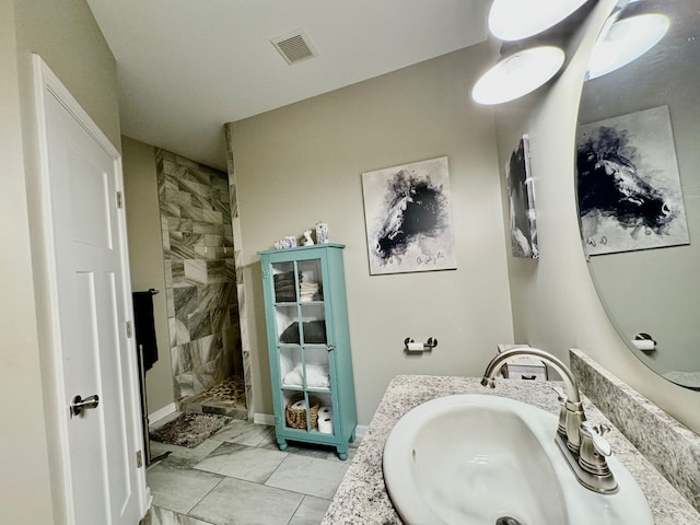 bathroom with tiled shower and vanity