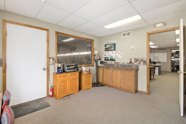 kitchen featuring light carpet and a drop ceiling