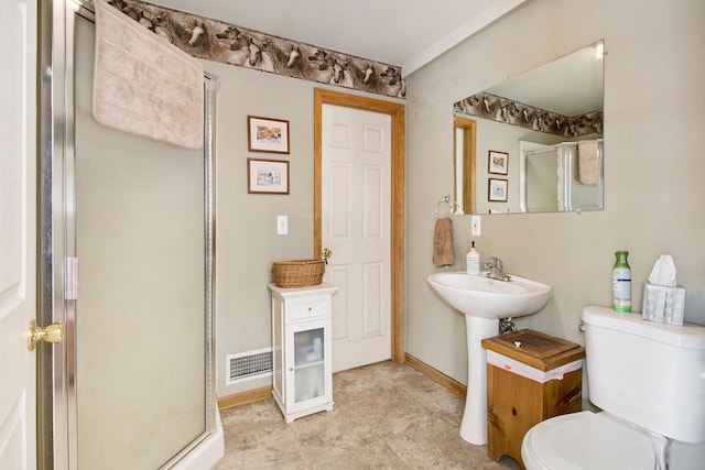 bathroom featuring sink, a shower with shower door, and toilet