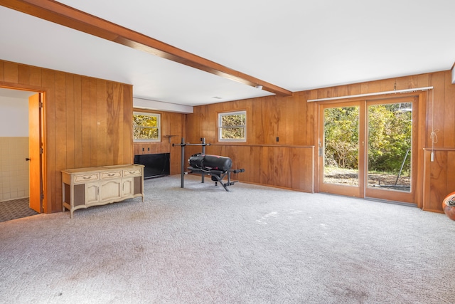 interior space with beamed ceiling, a healthy amount of sunlight, and wood walls