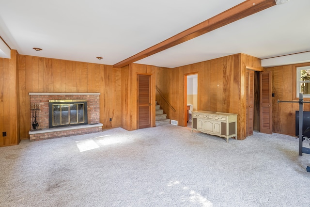 unfurnished living room featuring wooden walls, a fireplace, and carpet