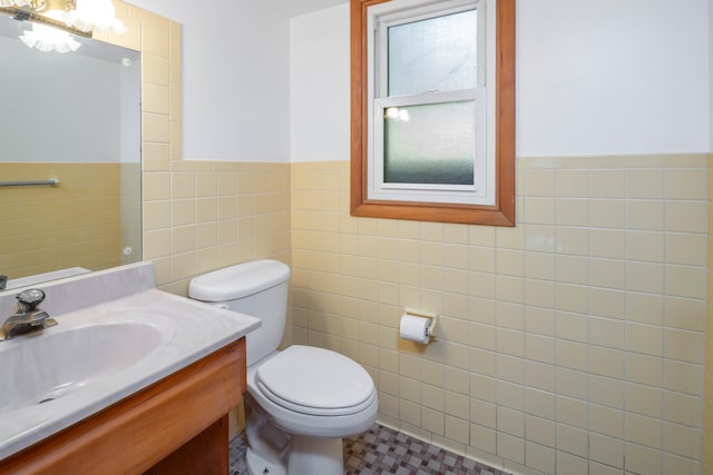 bathroom featuring tile patterned floors, vanity, toilet, and tile walls