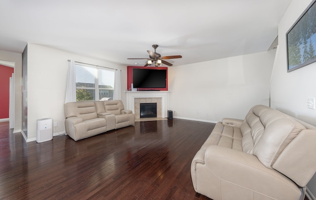 living room featuring a tile fireplace, dark hardwood / wood-style flooring, and ceiling fan