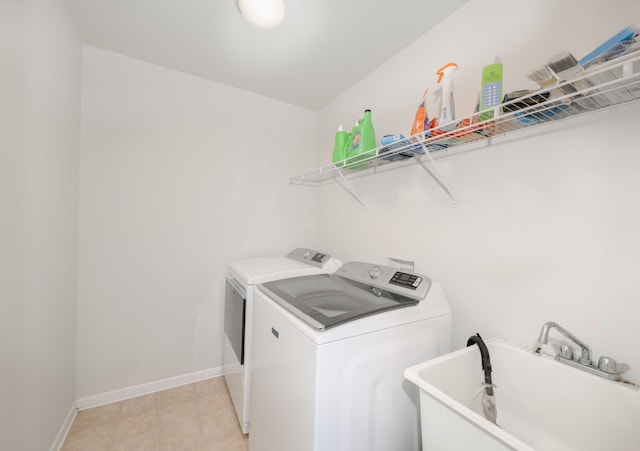 laundry area with separate washer and dryer, sink, and light tile patterned floors