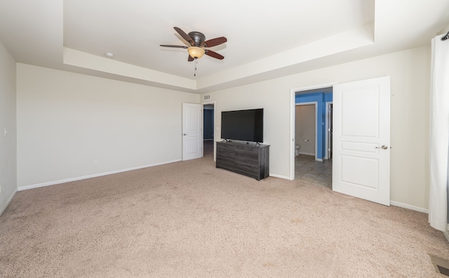 unfurnished bedroom featuring light carpet, a raised ceiling, and ceiling fan