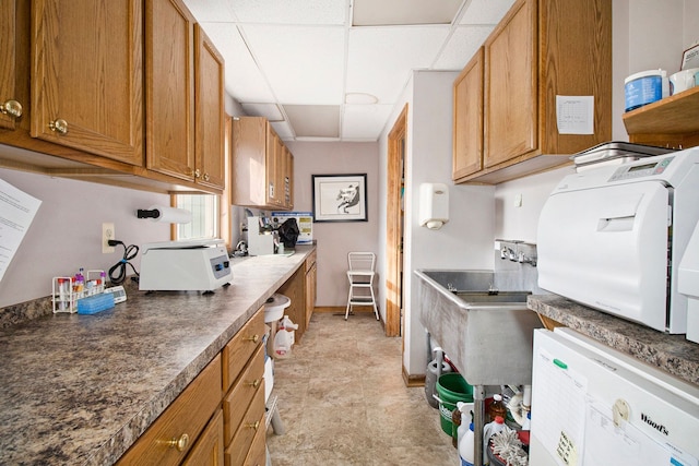 kitchen featuring a drop ceiling, washing machine and dryer, and sink