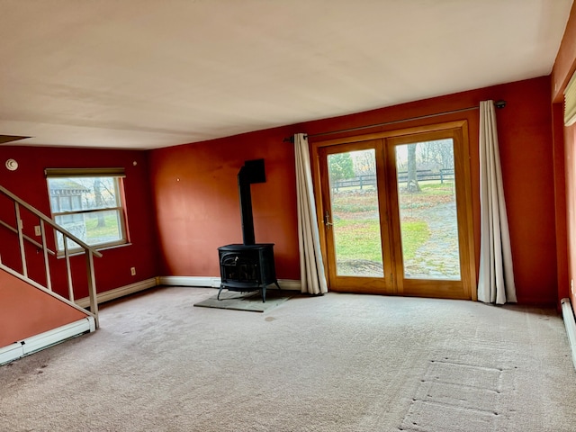 unfurnished living room with carpet flooring, a healthy amount of sunlight, and a wood stove