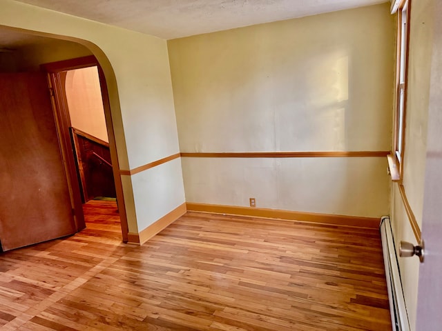 unfurnished room featuring light wood-type flooring and baseboard heating