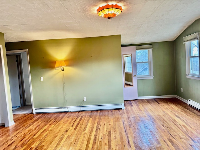 spare room with baseboard heating and light wood-type flooring