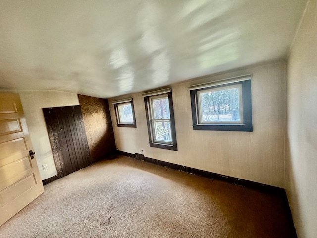 unfurnished room featuring carpet and vaulted ceiling