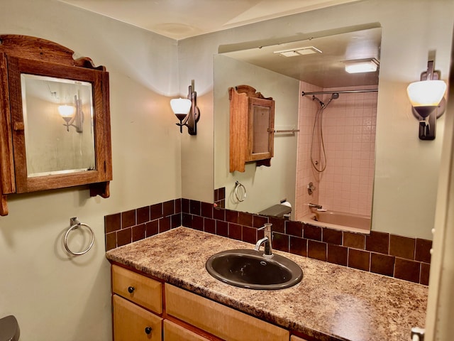 bathroom featuring tiled shower / bath combo, decorative backsplash, and vanity