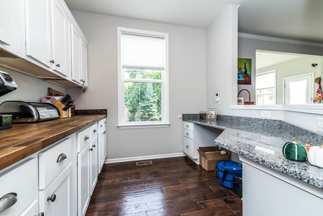 kitchen featuring butcher block countertops, dark hardwood / wood-style flooring, white cabinetry, and ornamental molding