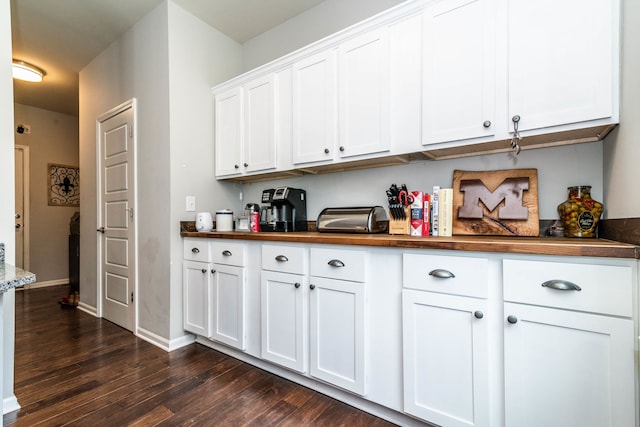 kitchen featuring dark wood-type flooring, white cabinetry, and butcher block countertops