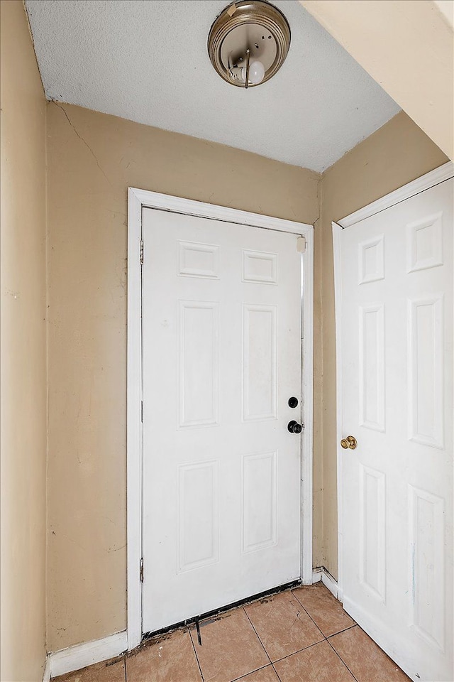 doorway to outside with light tile patterned floors and a textured ceiling