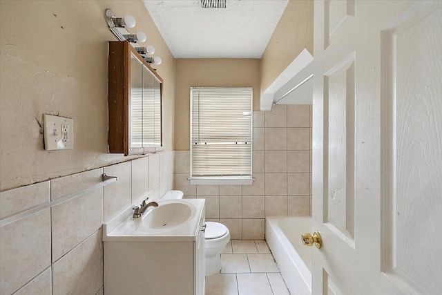 bathroom with a washtub, tile patterned flooring, a textured ceiling, vanity, and tile walls