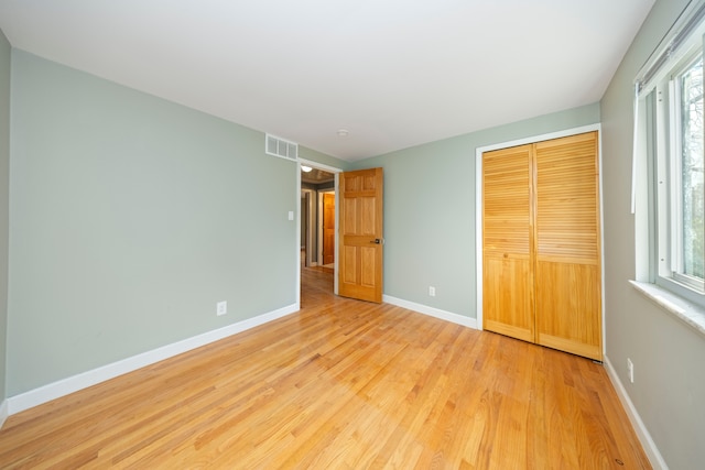 unfurnished bedroom featuring multiple windows, a closet, and light hardwood / wood-style floors