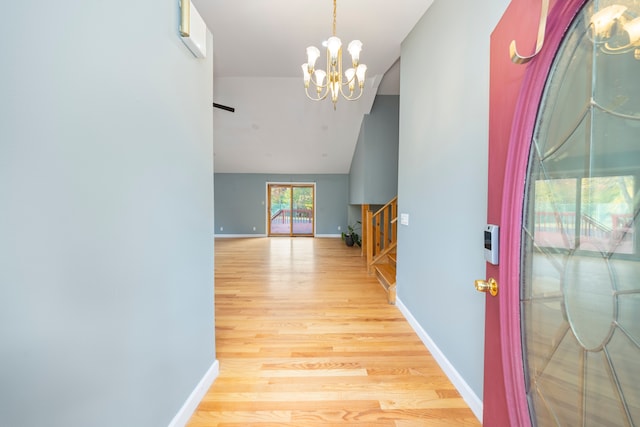 foyer entrance featuring light hardwood / wood-style flooring, a chandelier, and lofted ceiling