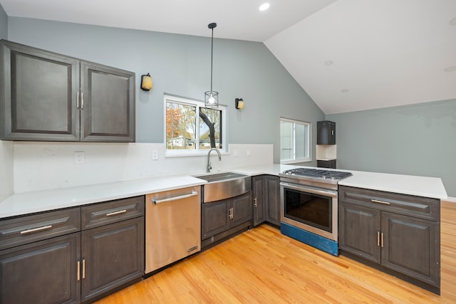 kitchen with sink, stainless steel appliances, kitchen peninsula, lofted ceiling, and light wood-type flooring