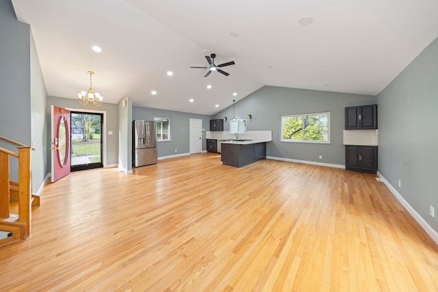 unfurnished living room featuring sink, ceiling fan with notable chandelier, light hardwood / wood-style floors, and lofted ceiling