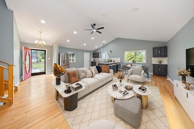 living room featuring light hardwood / wood-style flooring, ceiling fan with notable chandelier, lofted ceiling, and sink