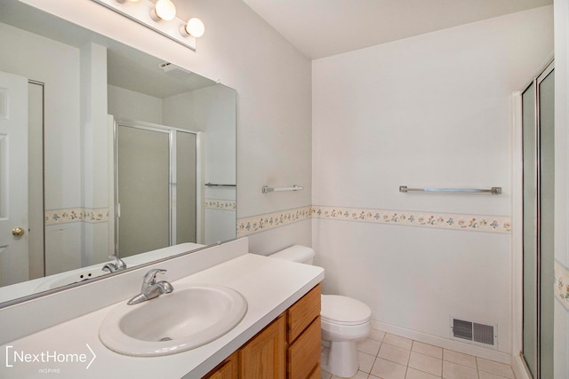 bathroom featuring tile patterned flooring, vanity, toilet, and a shower with shower door