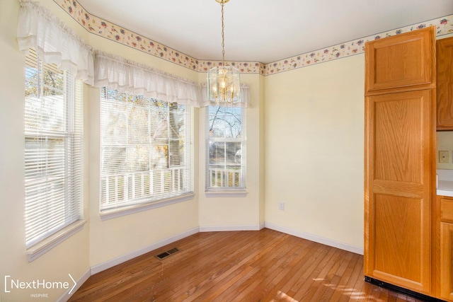 unfurnished dining area featuring hardwood / wood-style flooring and an inviting chandelier