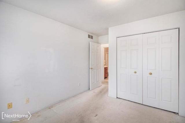 unfurnished bedroom with light carpet and a closet