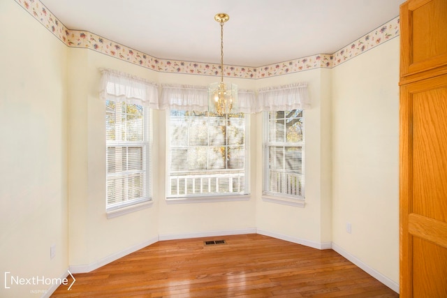 unfurnished dining area with a chandelier, light hardwood / wood-style floors, and a wealth of natural light