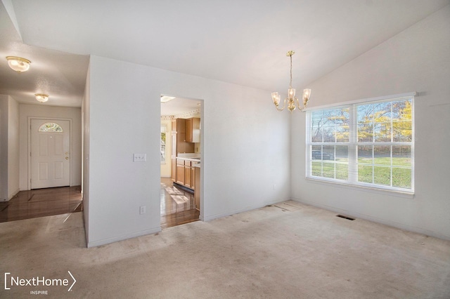 empty room featuring light colored carpet, lofted ceiling, and a notable chandelier