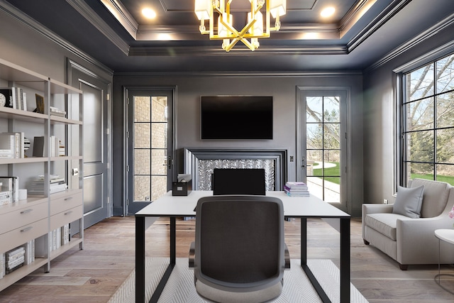 home office featuring a tray ceiling, crown molding, wood-type flooring, an inviting chandelier, and a fireplace