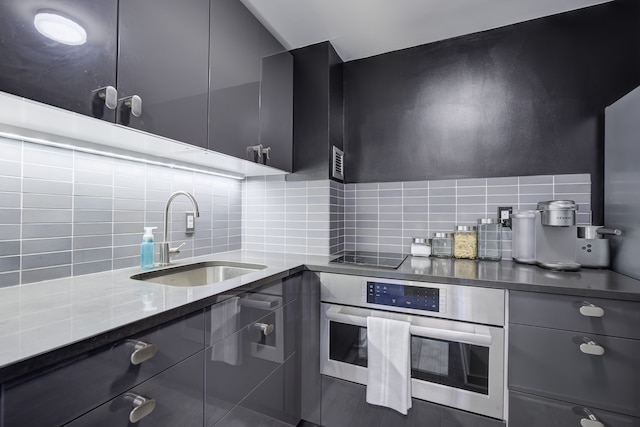 kitchen featuring sink, backsplash, oven, dark stone counters, and black electric stovetop