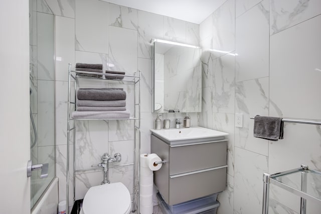 bathroom with vanity, toilet, and tile walls