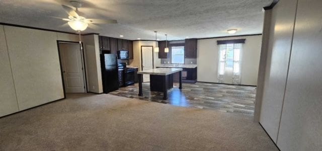 kitchen featuring a center island, a kitchen breakfast bar, pendant lighting, dark brown cabinets, and carpet