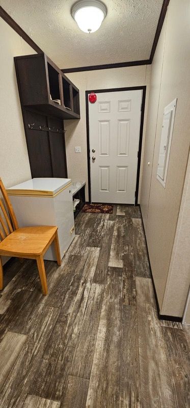 mudroom featuring a textured ceiling, ornamental molding, and dark wood-type flooring