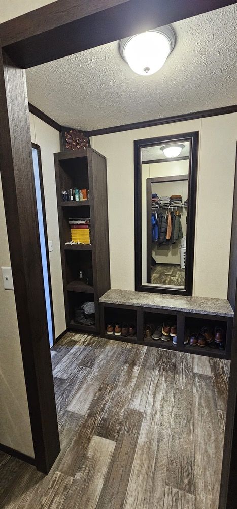 corridor with dark hardwood / wood-style floors, crown molding, and a textured ceiling