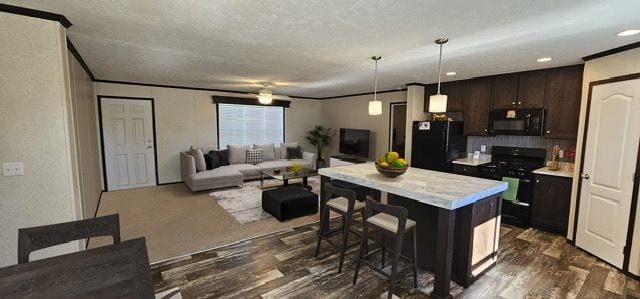 kitchen with a kitchen breakfast bar, dark hardwood / wood-style floors, dark brown cabinets, a kitchen island, and black appliances