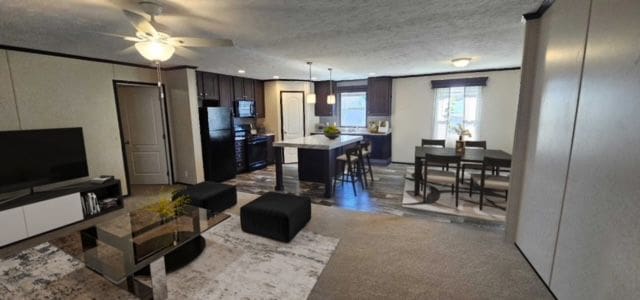 carpeted living room featuring ceiling fan and a textured ceiling